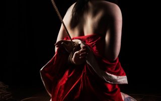 Shibari bondage emotion. Tattooed model tied in red juban. Bondage images by WykD Dave & Clover.